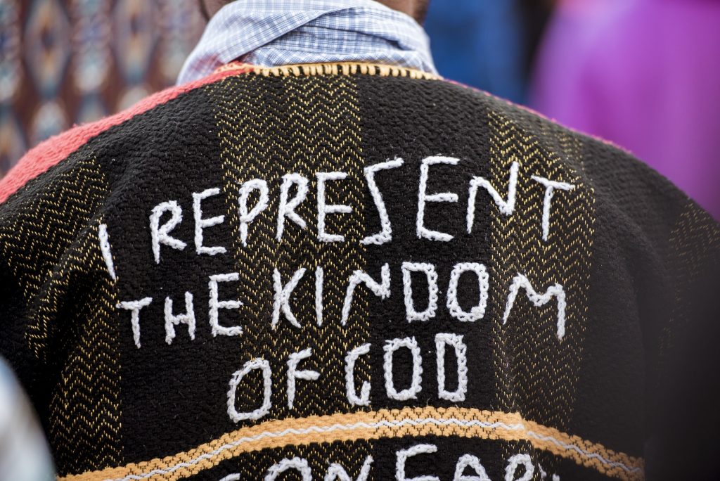 Closeup shot of a person's back wearing a coat with "I represent the kingdom of God" sewn on it